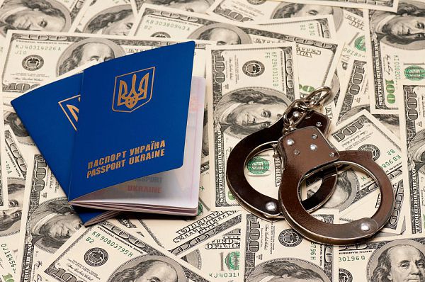 Two international Ukrainian passport with handcuffs on US dollars background